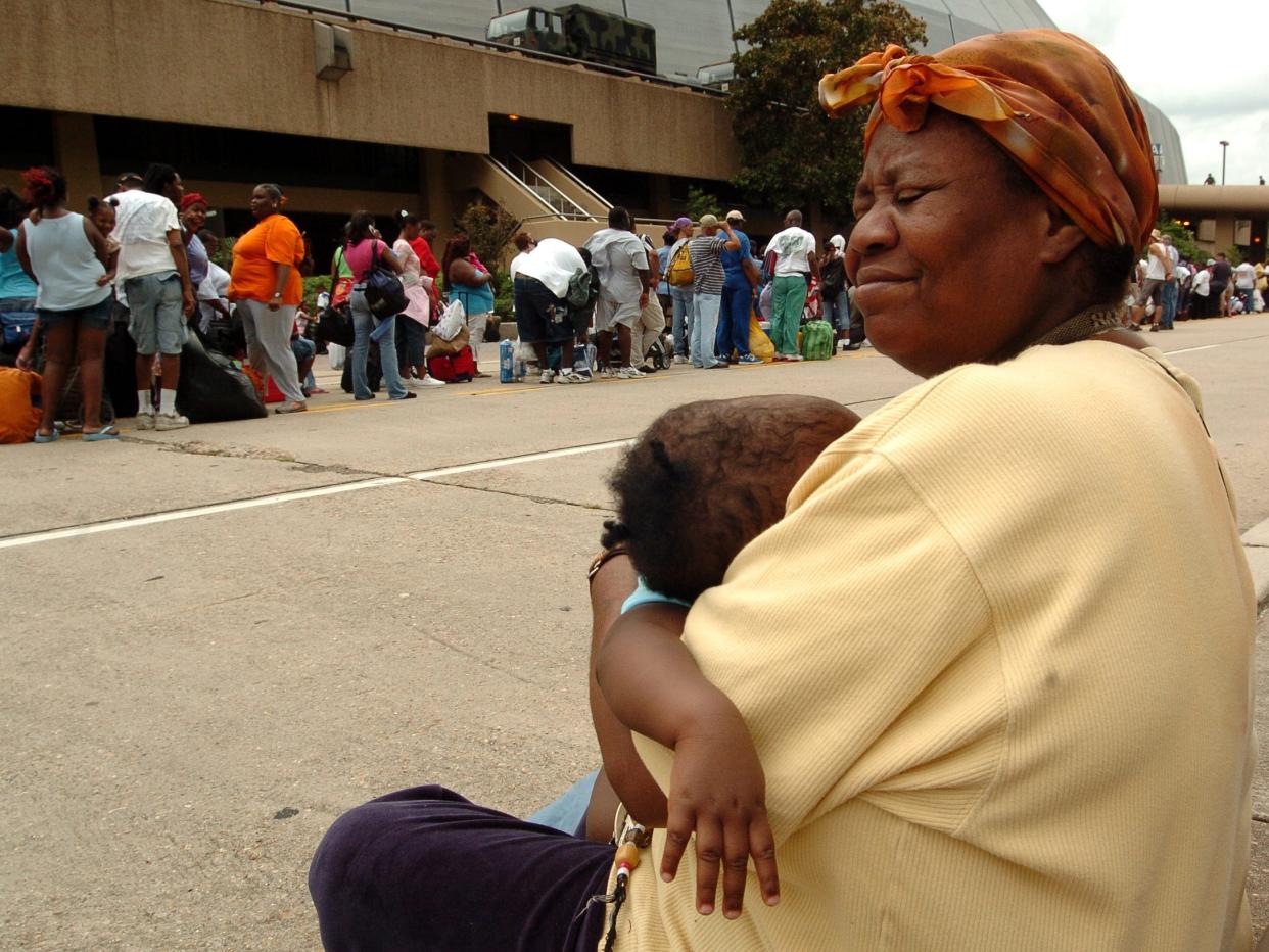 An unidentified woman holds a child while hurricane evacuees wait in line to enter the Super Dome in downtown New Orleans, Louisiana on August 28, 2005. The Dome was converted to a shelter for people with special needs and for those who have not evacuated the city as Hurricane Katrina approaches Louisiana as category five storm.