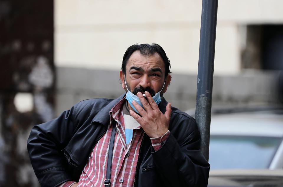 A Lebanese man smokes a cigarette as he wears a protective mask at a street in Beirut on March 12, 2020. - Lebanon yesterday suspended flights from countries hit hardest by the novel coronavirus after announcing its second death from the pandemic in two days. The Mediterranean nation has recorded at least 61 cases of COVID-19. Prime Minister Hassan Diab said Lebanon would suspend all trips to and from Italy, South Korea, Iran and China, the hardest hit countries. (Photo by JOSEPH EID / AFP) (Photo by JOSEPH EID/AFP via Getty Images)