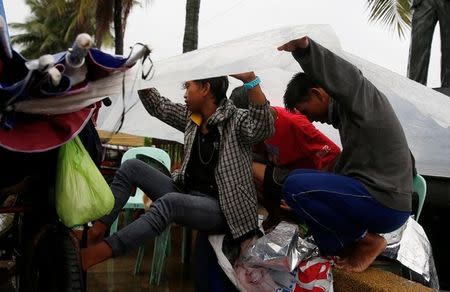 Vendors take shelter under a plastic sheet in Manila after Typhoon Karen slammed central and northern Philippines, October 16, 2016. REUTERS/Erik De Castro