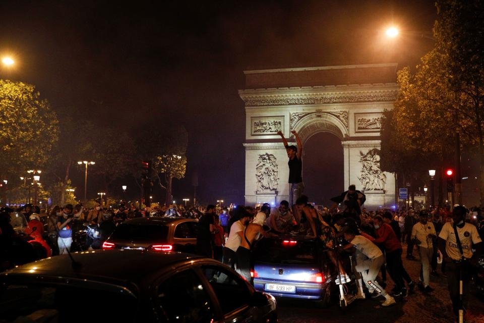 Paris Saint-Germain supporters celebrate their team's 3-0 win over RB Leipzig at the Champs-Elysees Avenue near the Arc de Triomphe in Paris on late August 18, 2020 following the UEFA Champions League semi-final football match between Leipzig and Paris Saint-Germain, played in Lisbon. - Paris Saint-Germain are through to the final of the Champions League for the first time after goals by Marquinhos, Angel Di Maria and Juan Bernat saw them ease to a 3-0 win over RB Leipzig in a one-sided semi-final in Lisbon on August 18. (Photo by GEOFFROY VAN DER HASSELT / AFP) (Photo by GEOFFROY VAN DER HASSELT/AFP via Getty Images)