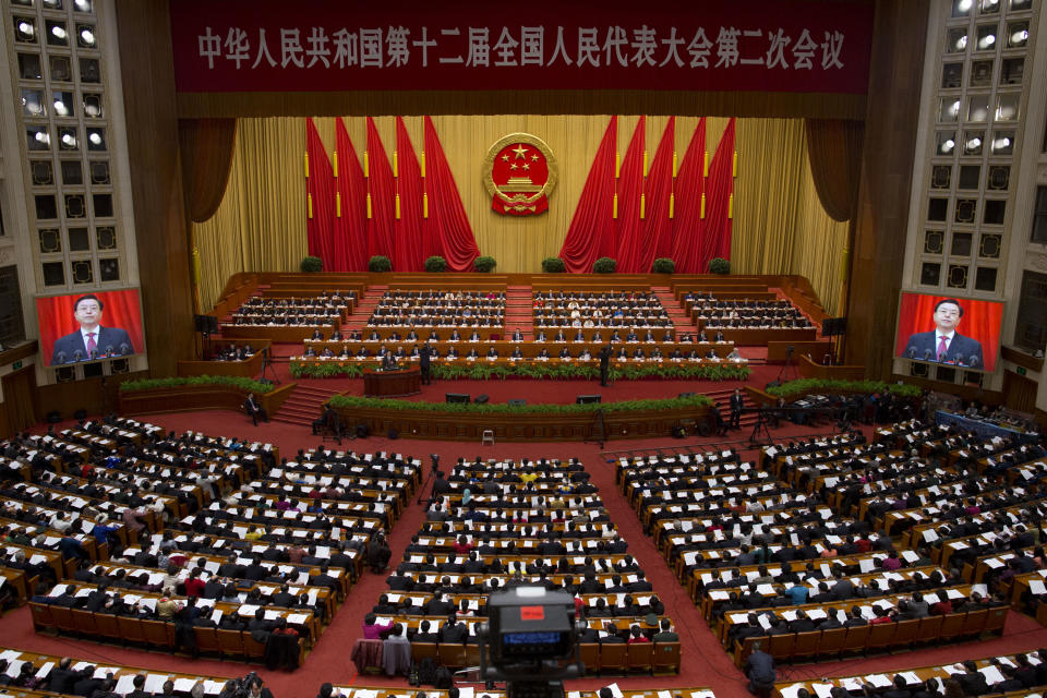 Zhang Dejiang, chairman of the National People's Congress, reads a work report as his image is shown on screens inside the main hall of the Great Hall of the People during a plenary session of the annual National People's Congress in Beijing, China, Sunday, March 9, 2014. (AP Photo/Alexander F. Yuan)