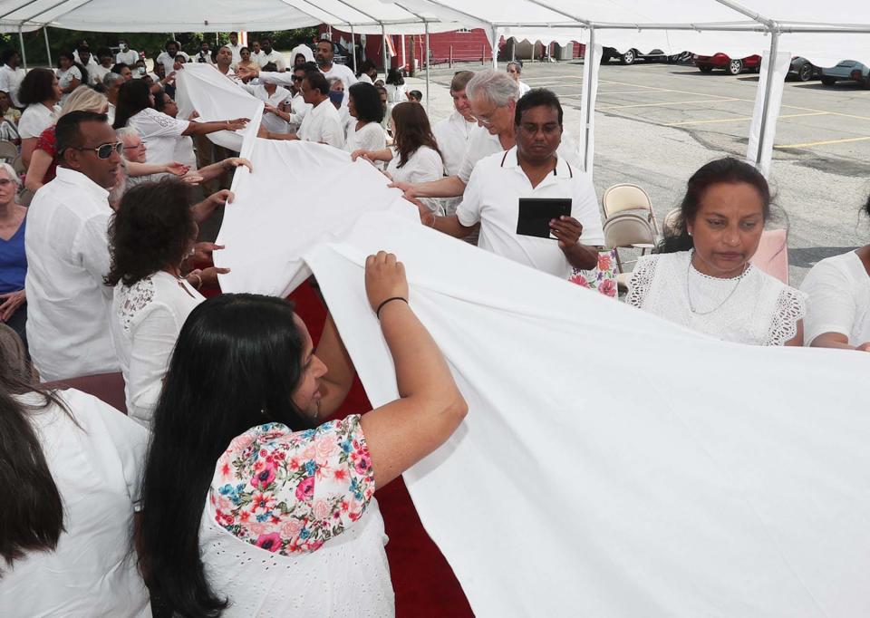 Those in attendance touch the ceremonial cloth before it is presented to the monks Saturday.