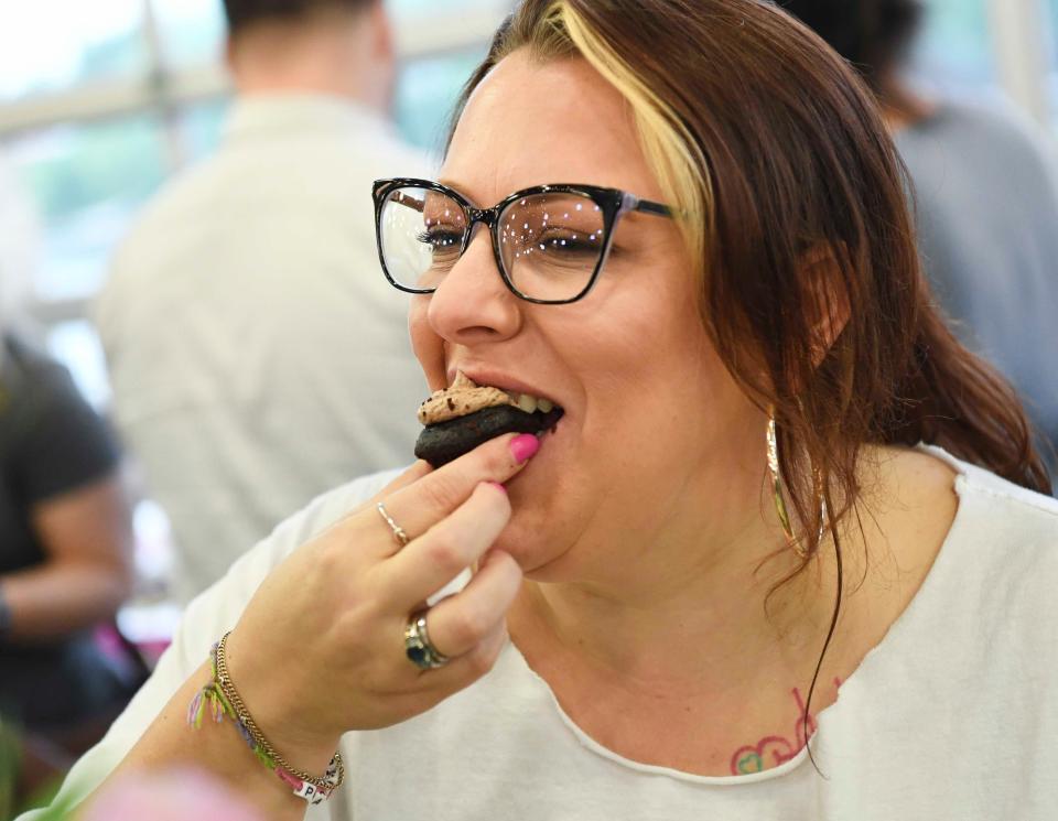 Victoria Mallon takes a bite of a Brooklyn black cake that was featured by the Cookie Boutique during the Death by Chocolate fundraiser for Family Counseling Service on April 18, 2024, at the Tuscaloosa River Market.