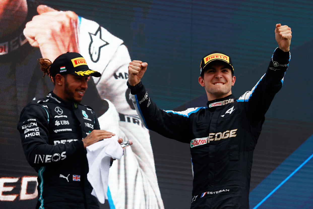 Race winner Esteban Ocon celebrates on the podium next to Lewis Hamilton.
