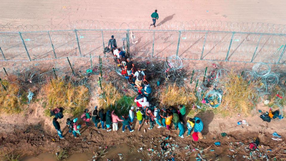 PHOTO: Immigrants pass through razor wire while crossing the U.S.-Mexico border on March 13, 2024, in El Paso, Texas. The wire was placed by the troops as part of Texas Gov. Greg Abbott's 'Operation Lone Star' to deter migrants from crossing into Texas. (John Moore/Getty Images, FILE)