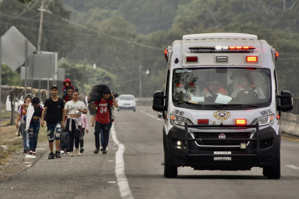 An ambulance drives past migrants walking to Huehuetan, Chiapas state, Mexico, Monday, April 24, 2023. About 3,000 migrants began walking before dawn for a second day of protest march demanding the end of detention centers like the one that caught fire last month, killing 40 migrants. (AP Photo/Edgar H. Clemente)