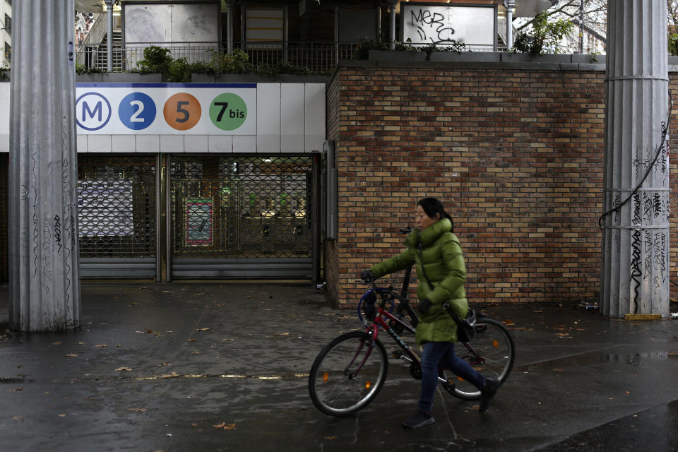 A woman pulls her bicycle by a closed subway station Friday, Dec. 6, 2019 in Paris. Frustrated travelers are meeting transportation chaos around France for a second day, as unions dig in for what they hope is a protracted strike against government plans to redesign the national retirement system. (AP Photo/Rafael Yaghobzadeh)