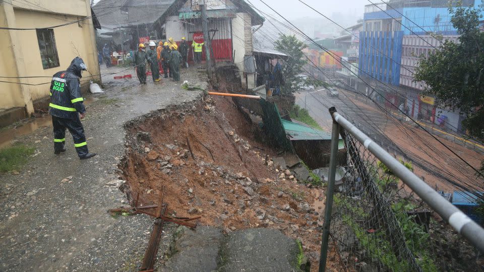 A police officer checks a landslide caused by the typhoon at a residential area in Baguio City, northern Philippines. - AP