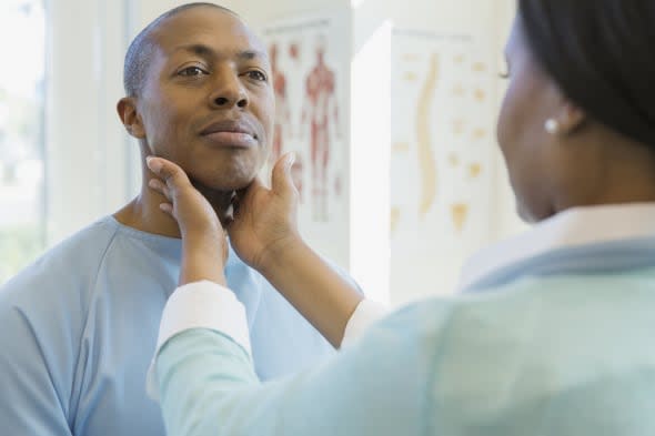 Female doctor examining male patient's glands in clinic