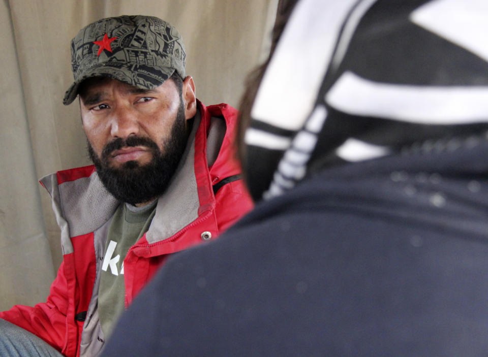 Ibrahim Rasool, Afghan refugee, formerly a FIFA-licensed futsal referee sits with other migrants around a fire at a makeshift camp housing migrants, in Velika Kladusa, Bosnia, Saturday, Nov. 13, 2021. Ibrahim Rasool loved his job as a futsal referee because of sportsmanship and fair play. But the 33-year-old man from Afghanistan says there is nothing fair about the way the European Union treats people seeking refuge from violence and war. (AP Photo/Edvin Zulic)