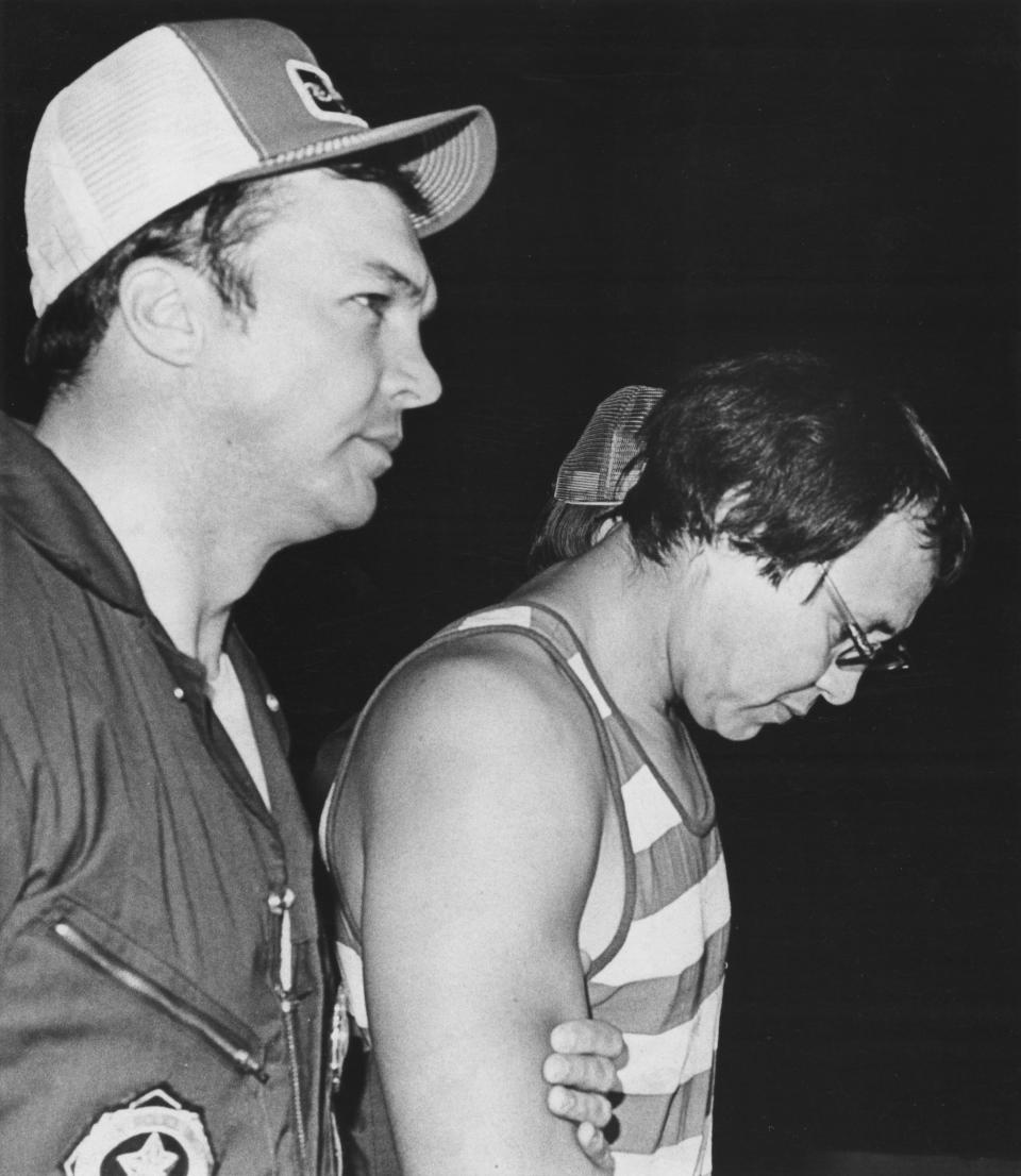 Gene Leroy Hart, accused of slaying three Girl Scouts near Locust Grove in summer 1977, waits with head bowed outside Oklahoma State Penitentiary, accompanied by Oklahoma State Bureau of Investigation agent Larry Bowles.