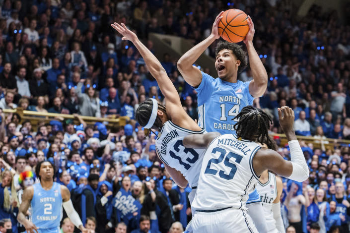 North Carolina forward Puff Johnson (14) looks to shoot while guarded by Duke guard Jacob Grandison (13) and forward Mark Mitchell (25) in the first half of an NCAA college basketball game on Saturday, Feb. 4, 2023, in Durham, N.C. (AP Photo/Jacob Kupferman)