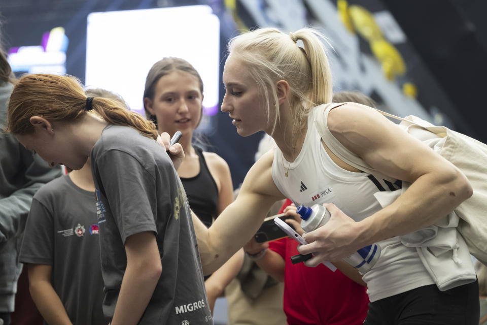 FILE - Slovenia's Janja Garnbret, right, signs an autograph at the IFSC Climbing World Championship 2023 in Bern, Switzerland, Wednesday, Aug. 2, 2023. Garnbret, an eight-time world champion and defending Olympic gold medalist, attracted headlines last year when she spoke out on Instagram about the problems of eating disorders: “Do we want to raise the next generation of skeletons? Let’s not look away.” The 25-year-old Garnbret said she became concerned when she started hearing young girls “talking about how if they lost some weight, they would be just as good” as the other girls who were winning. (Anthony Anex/Keystone via AP, File)