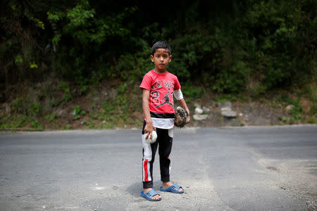 Luis Mejia, 7, poses for a picture after practice baseball on the street in Caracas, Venezuela August 29, 2017. REUTERS/Carlos Garcia Rawlins/Files