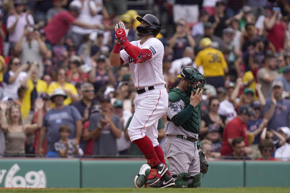 Boston Red Sox's Adam Duvall, left, celebrates after his home run in front of Oakland Athletics' Manny Pina, right, as he arrives home in the sixth inning of a baseball game, Sunday, July 9, 2023, in Boston. (AP Photo/Steven Senne)