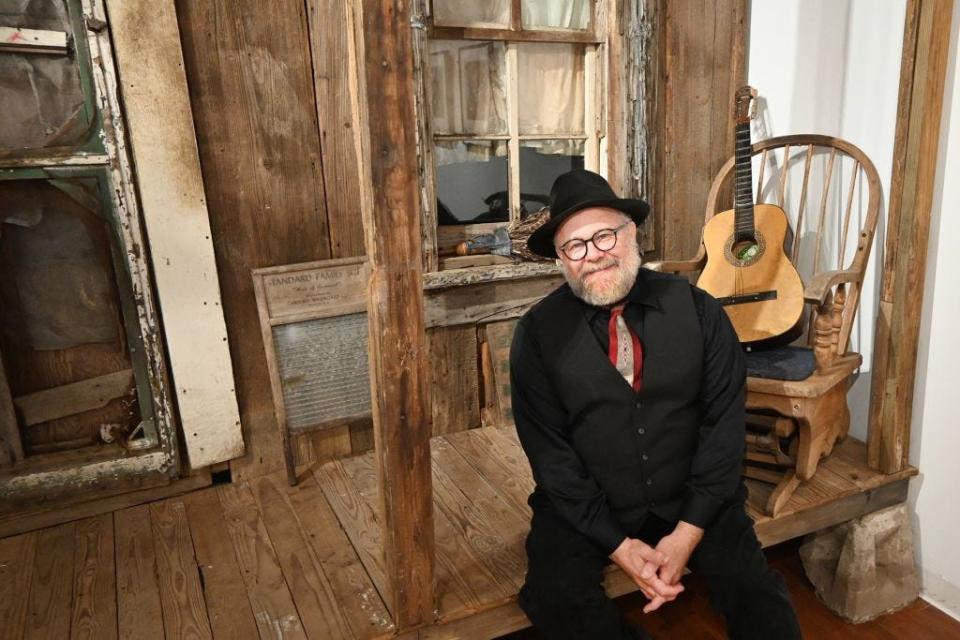 Photojournalist and MTSU alumnus Bill Steber sits on the porch of a facade of a salvaged Mississippi Delta sharecropper's shack that is part of his exhibit, "Deep Roots: Evocations of the Mississippi Delta Blues," on display through Dec. 9, 2023, in Middle Tennessee State University's Baldwin Photographic Gallery. (MTSU photo by Nancy DeGennaro)