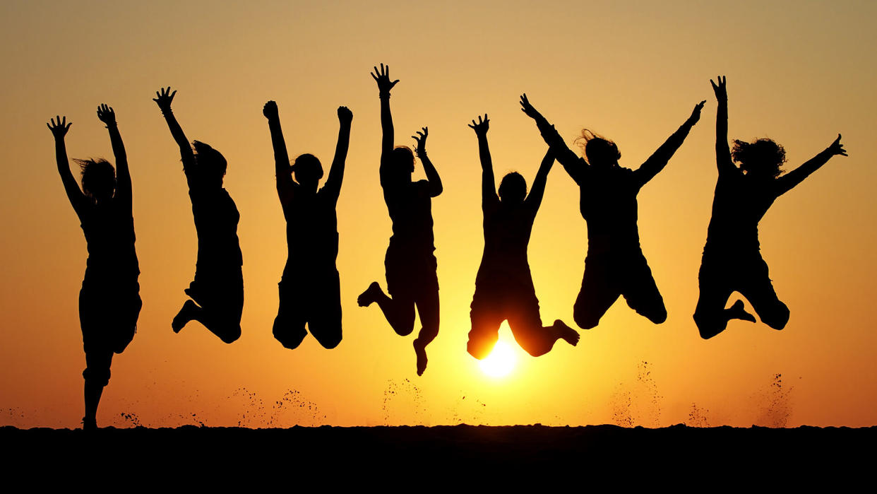 silhouette of friends jumping on beach during sunset time.