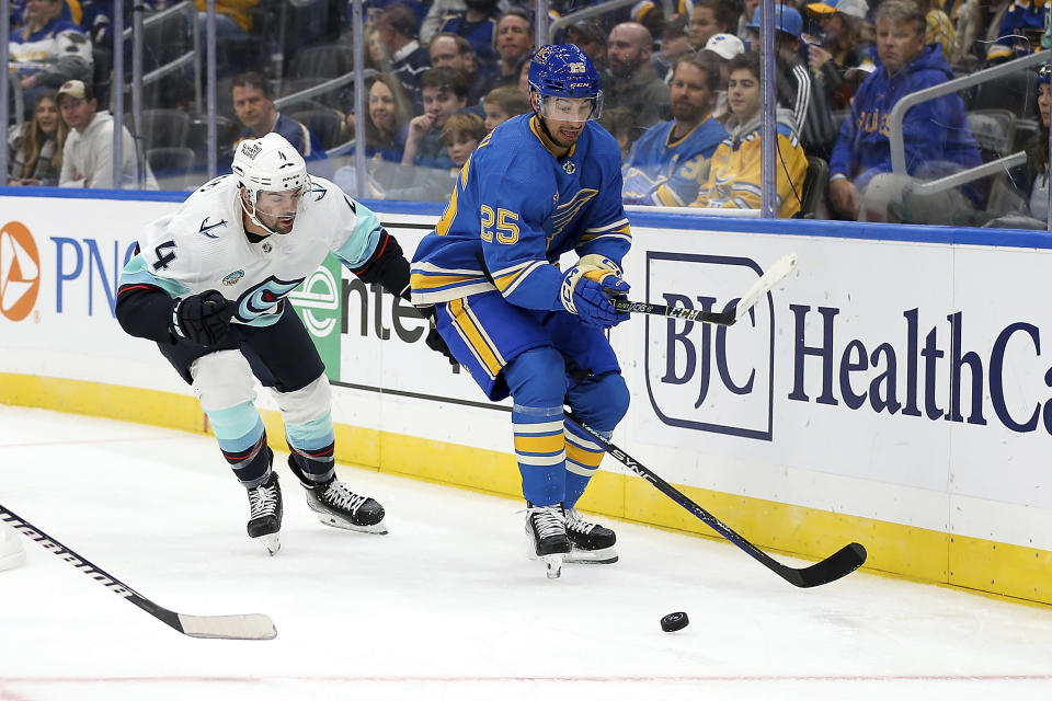 Seattle Kraken's Justin Schultz (4) and St. Louis Blues' Jordan Kyrou (25) vie for the puck during the second period of an NHL hockey game Saturday, Oct. 14, 2023, in St. Louis. (AP Photo/Scott Kane)