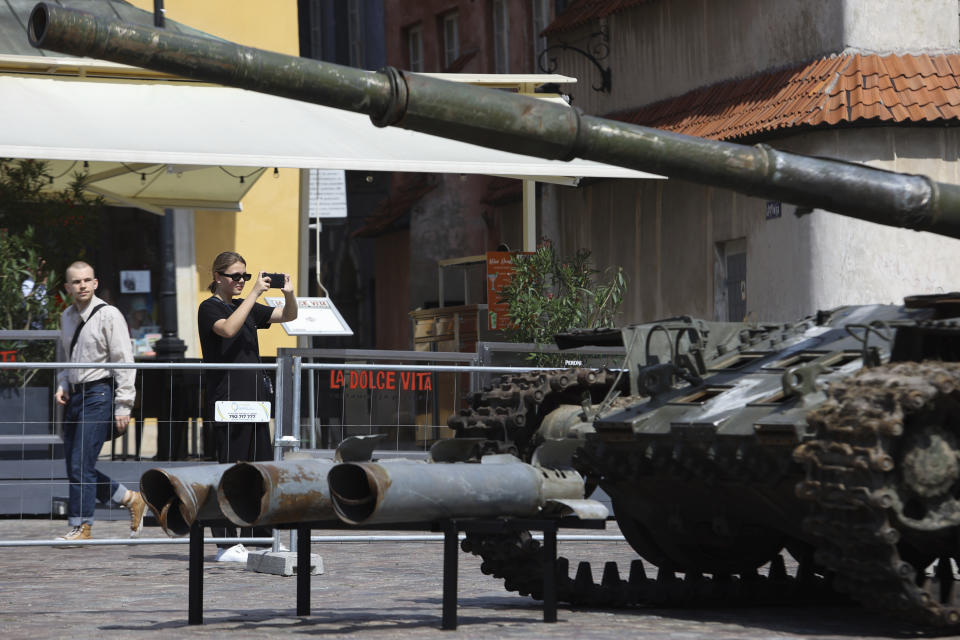 People visit an open-air exhibition of damaged and burnt-out Russian tanks and armored vehicles at the Castle Square, in Warsaw, Poland, Monday, June 27, 2022. The vehicles were captured by Ukrainian military forces during the war in the Ukraine. Ukrainian authorities announced that there are plans for similar exhibits in other European capitals such as Berlin, Paris, Madrid and Lisbon. (AP Photo/Michal Dyjuk)