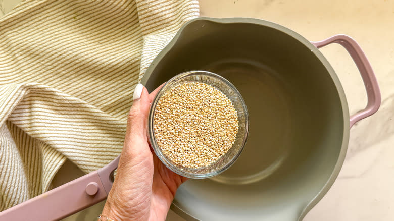 hand adding quinoa to pot
