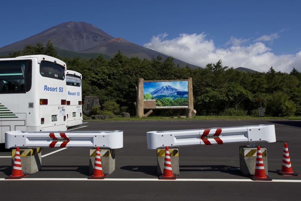 In this Thursday, Aug. 29, 2013 photo, tour buses, guard rails and a tourist information sign sit in a parking lot at the base of Mount Fuji. The recent recognition of the 3,776-meter (12,388-foot) peak as a UNESCO World Heritage site has many here worried that will draw still more people, adding to the wear and tear on the environment from the more than 300,000 who already climb the mountain each year. (AP Photo/David Guttenfelder)
