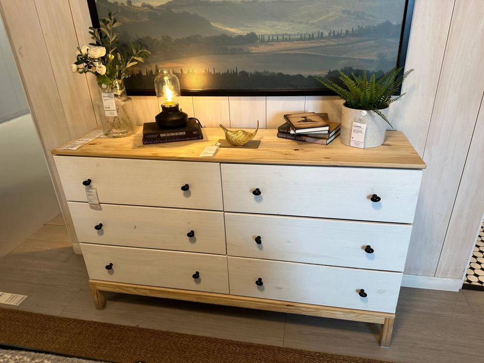 White dresser with natural wood top and black knobs