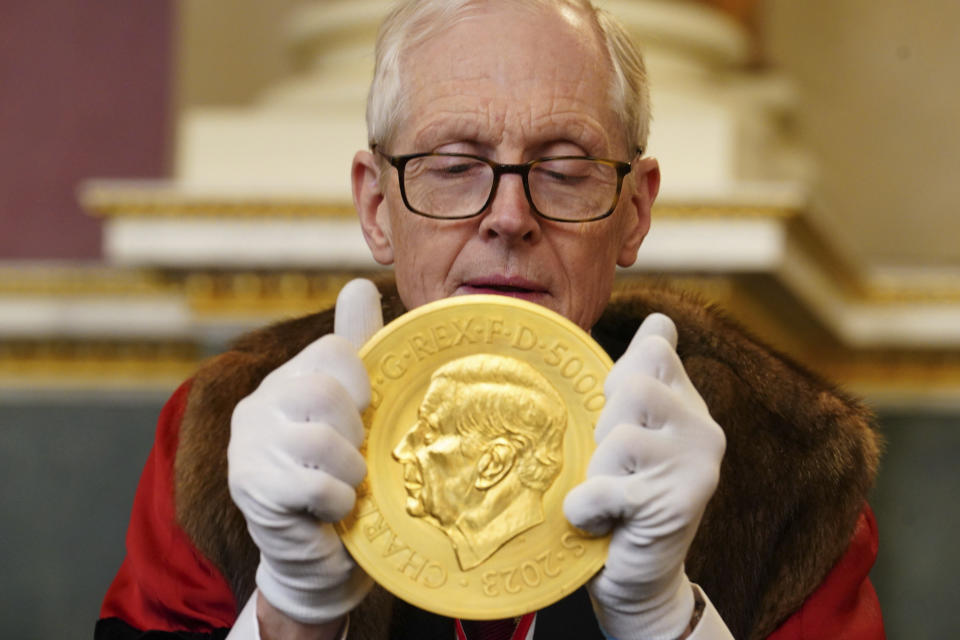 Professor Charles Mackworth-Young, prime warden of the Goldsmith's Company, inspects a new coin bearing the image of King Charles III, at Goldsmiths' Hall in London, Tuesday, Feb. 6, 2024, during the Trial of the Pyx, a judicial ceremony to ensure that newly minted coins from the Royal Mint conform to their required specifications. (Jordan Pettitt/PA via AP)