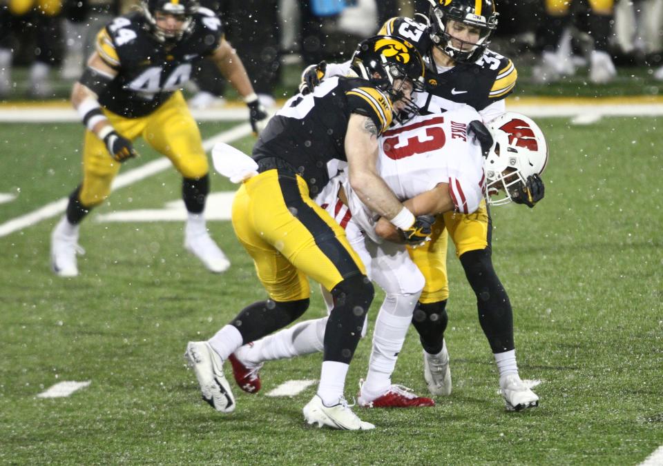 IOWA CITY, IOWA - DECEMBER 12:  Wide receiver Chimere Dike #13 of the Wisconsin Badgers is tackled during the second half by defensive backs Jack Koerner #28 and Riley Moss #33 of the Iowa Hawkeyes at Kinnick Stadium on December 12, 2020 in Iowa City, Iowa.  (Photo by Matthew Holst/Getty Images)