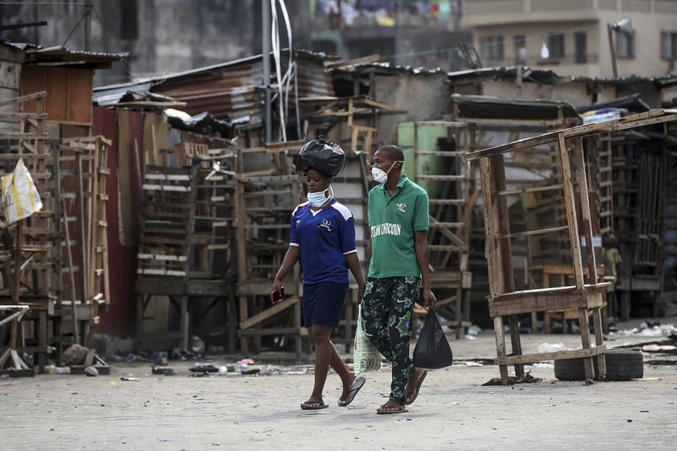 People walk past closed street stalls and shops due to a government ban on the operation of non-essential businesses and markets to halt the spread of the new coronavirus, in Lagos, Nigeria, on March 26, 2020.