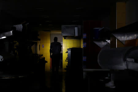 A man uses his phone's light as he walks at the kitchen of a restaurant during a blackout in Caracas, Venezuela March 7, 2019. REUTERS/Carlos Garcia Rawlins