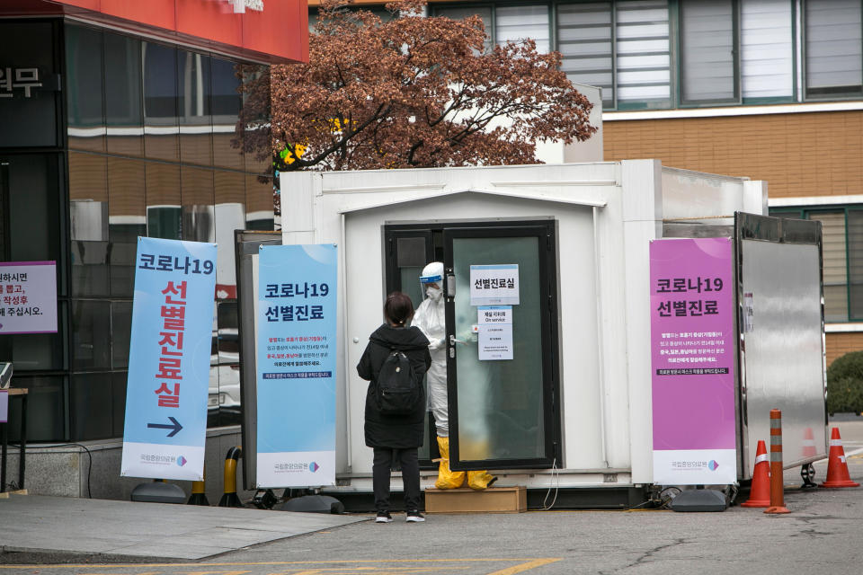 Un miembro del personal de un hospital ataviado con equipo de protección habla con una mujer que podría estar infectada de coronavirus en la entrada del Centro Médico Nacional de Seúl, Corea del Sur, el miércoles 26 de febrero de 2020. (Jean Chung/The New York Times)