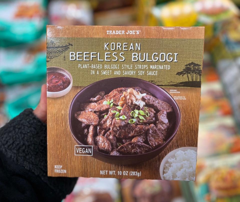 A hand is holding a brown box with a photo of a beefless Korean bulgogi with green onions on it
