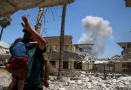 <p>A displaced Iraqi resident carries his child overlooking a smoke billowing due to fighting between Iraqi forces and Islamic State militants near the Old City in western Mosul, Iraq June 13, 2017. (Photo: Erik De Castro/Reuters) </p>