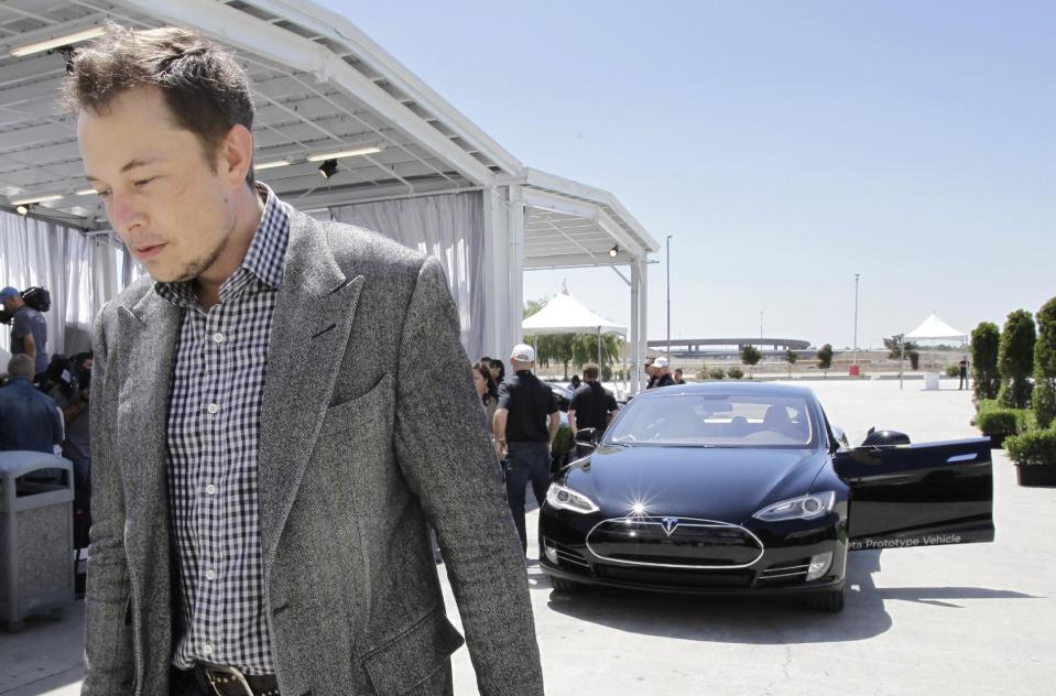Tesla CEO Elon Musk walks past the Tesla Model S after a news conference at the Tesla factory in Fremont, Calif., Friday, June 22, 2012. The first Model S sedan car will be rolling off the assembly line on Friday. (AP Photo/Paul Sakuma)