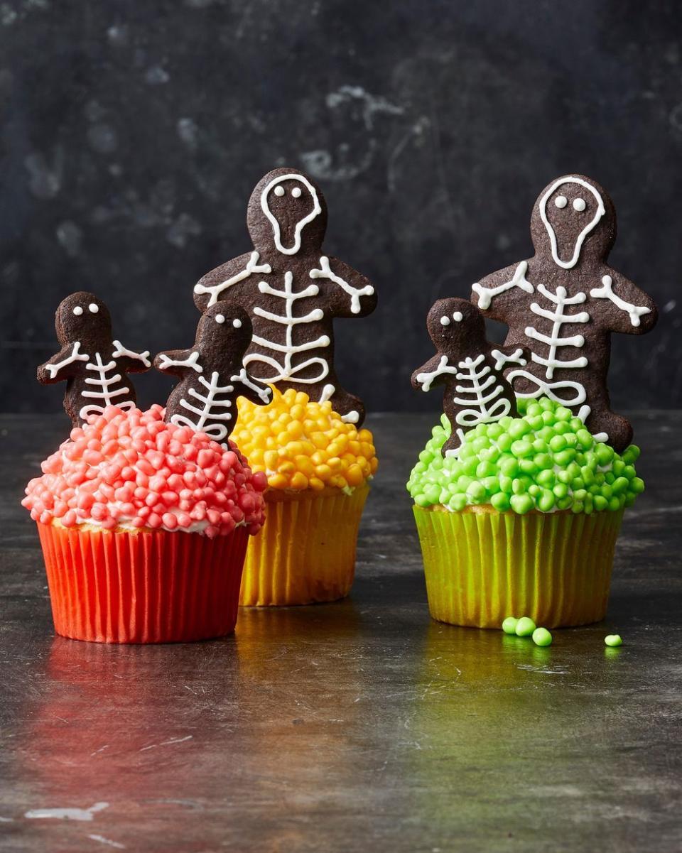 <p>Neon candy-covered cupcakes are the perfect resting place for this skeleton cookie family. </p><p>Get the <a href="https://www.goodhousekeeping.com/food-recipes/party-ideas/a28592955/chocolate-skeleton-cookie-cupcakes-recipe/" rel="nofollow noopener" target="_blank" data-ylk="slk:Chocolate Skeleton Cookie Cupcakes recipe;elm:context_link;itc:0;sec:content-canvas" class="link "><strong>Chocolate Skeleton Cookie Cupcakes recipe</strong></a><em>.</em></p>