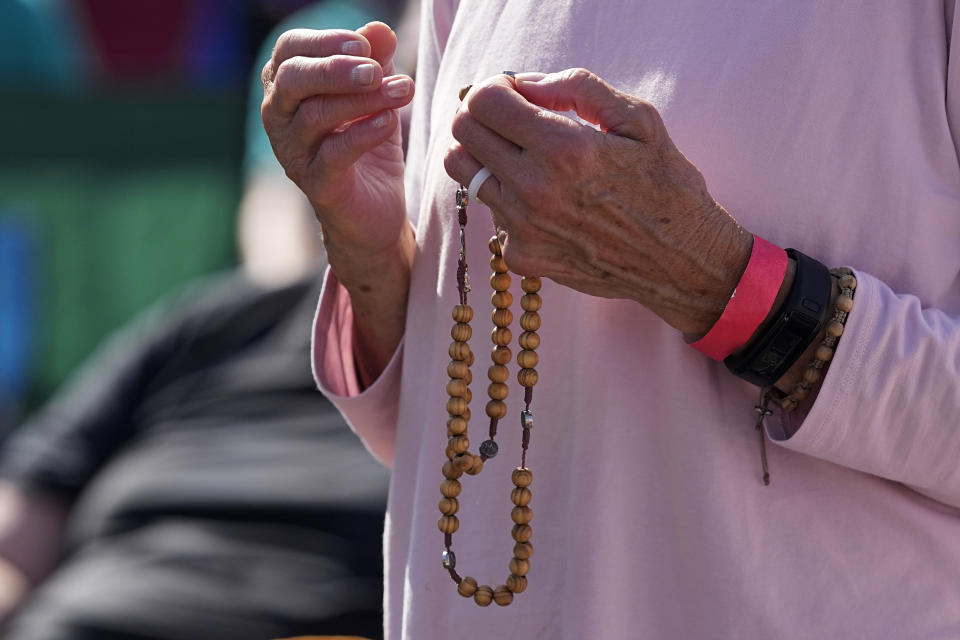 An attendee holds a rosary as she prays during a "rosary rally" on Sunday, Aug. 6, 2023, in Norwood, Ohio. A national religious organization, Catholics for Catholics, gathered a lineup of anti-abortion influencers and conspiracy theorists from across the U.S. to speak at the rally to urge a “yes” vote on a ballot question in Ohio, known as Issue 1. If voters approve Issue 1, it would make it more difficult for an abortion rights amendment on the November ballot to succeed. (AP Photo/Darron Cummings)