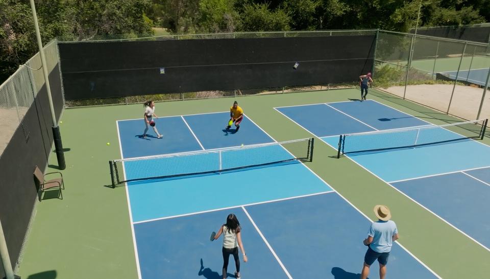 Drone shot of a mixed doubles game of pickleball. Another game is going on in the next court.