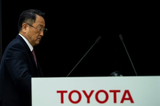 Akio Toyoda, president of Japan's auto giant Toyota Motor, walks past a logo of Toyota at the end of a press conference to announce the company's 2019 financial results