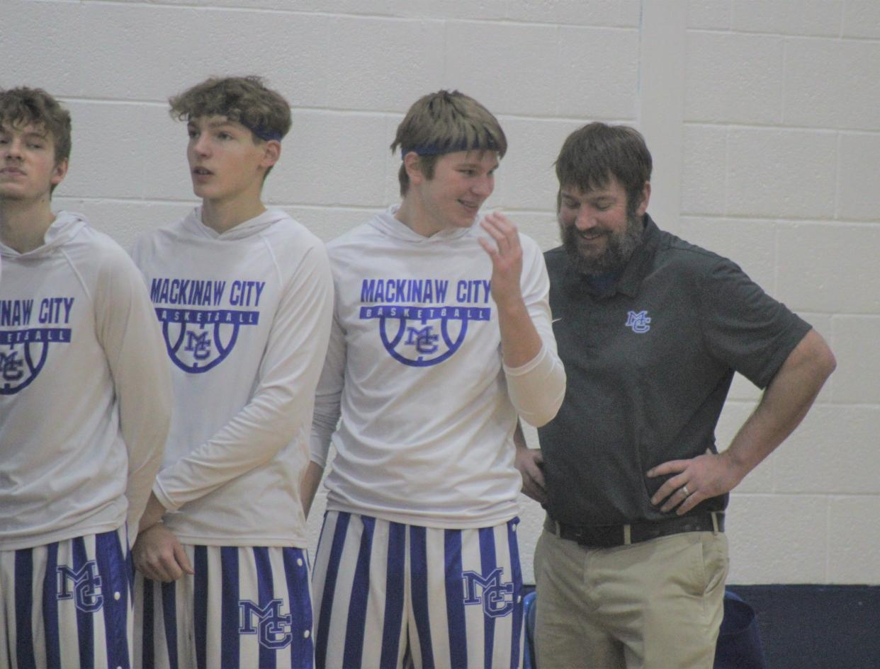 Mackinaw City senior Lucas Bergstrom and his father, assistant coach Bryan Bergstrom (right), share a laugh before a recent game against Boyne Falls. Lucas, a star for the Comets, has learned a lot under Bryan, who's coached his son since his elementary school days.