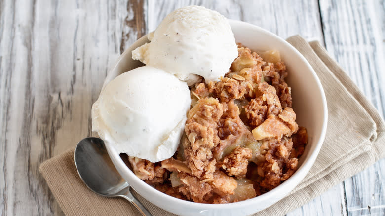 Bowl of apple crumble with two scoops of ice cream