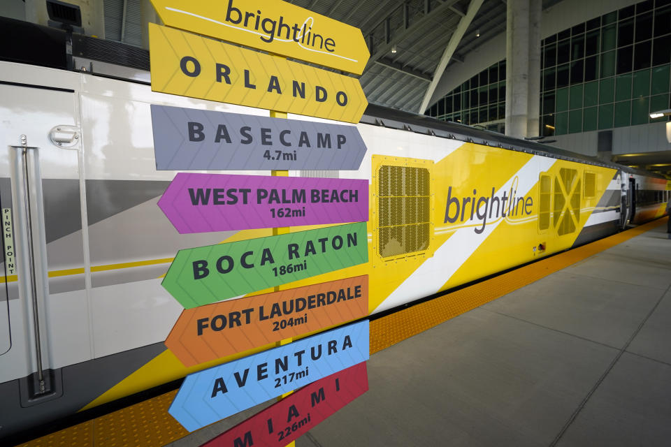 A sign post is seen in front of a Brightline rail car to celebrate the completion of the construction of the Brightline high speed rail on Wednesday, June 21, 2023, in Orlando, Fla. The rail system now connects Miami to Orlando. (AP Photo/John Raoux)