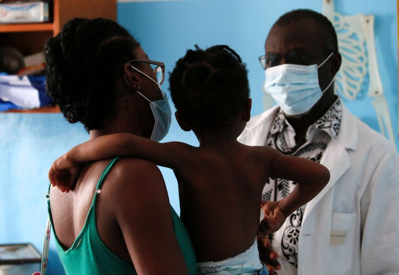 FILE PHOTO: Doctor Charles Eblin prepares to take care of a girl with malaria at his clinic Centre de sante sainte Marie de Marcory in Abidjan