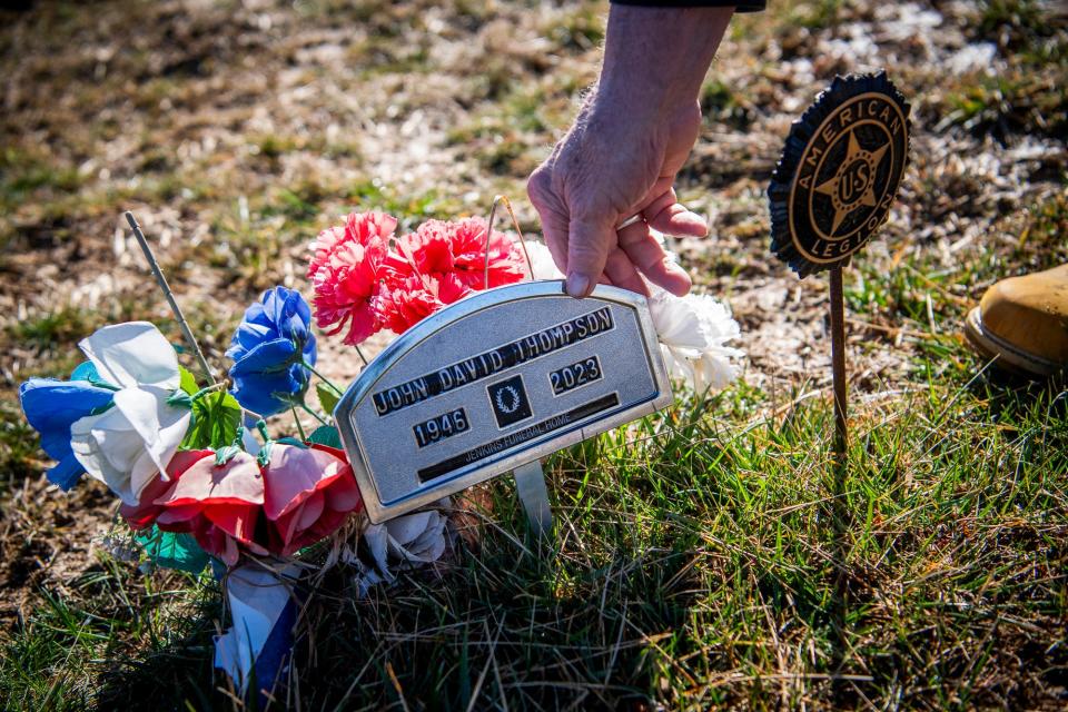 Jim Thompson straightens the nameplate at the gravesite for his brother, John Thompson, at the Solsberry Cemetery last week.