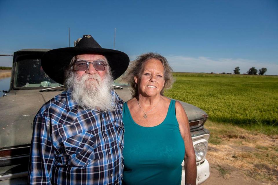 Frenchy Meissonnier, 72, left, and his wife Debi, 69, stand in front of a field of rice at Meissonnier Ranch, located along West Dickenson Ferry Road in Merced County, Calif., on Thursday, Aug. 11, 2022.