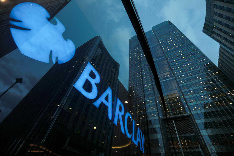 Signage shines through a window reflecting Barclays Plc head offices at the Canary Wharf business, financial and shopping district in London, U.K. Photo: Luke MacGregor/Bloomberg/Getty