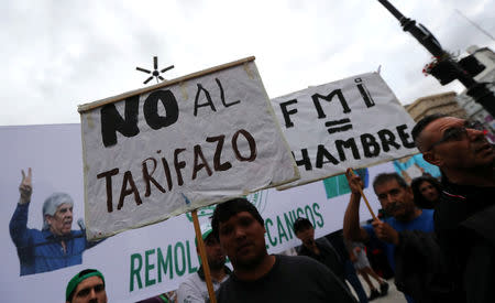 Demonstrators hold signs during a protest against a cost increase in public and utility services in Buenos Aires, Argentina, January 10, 2019. The signs reads "No to the increase in utility service tariffs" (L) and “IMF (International Monetary Fund) = Hunger". REUTERS/Marcos Brindicci