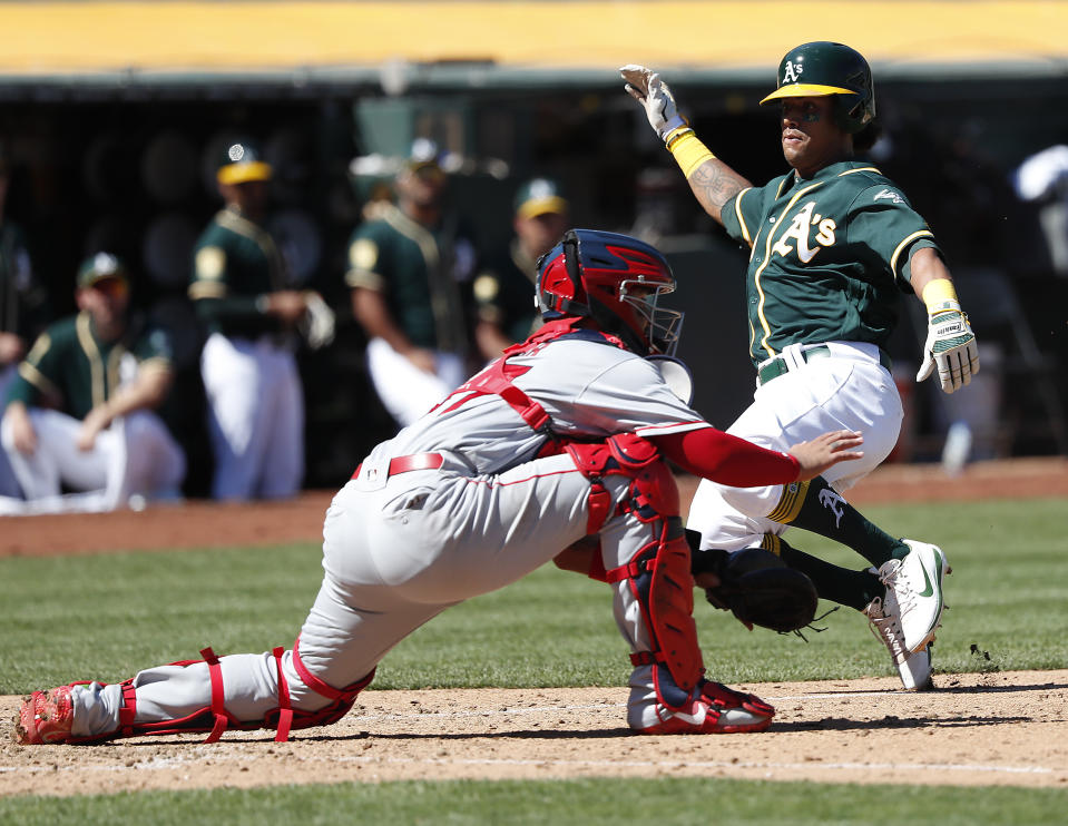Oakland Athletics' Khris Davis (2) slides past Los Angeles Angels catcher Francisco Arcia (37) to score on a run on a single by Stephen Piscotty during the fourth inning in a baseball game in Oakland, Calif., Thursday, Sept. 20, 2018. (AP Photo/Tony Avelar)