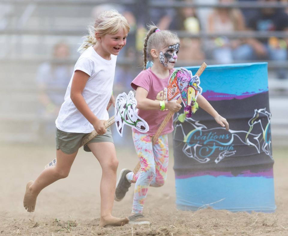 Journee Rhodes, 6, left, of Malvern and Elouise Zwick, 5, of Minerva, compete in the kids Stick Horse race at the Minerva Chamber Rodeo.