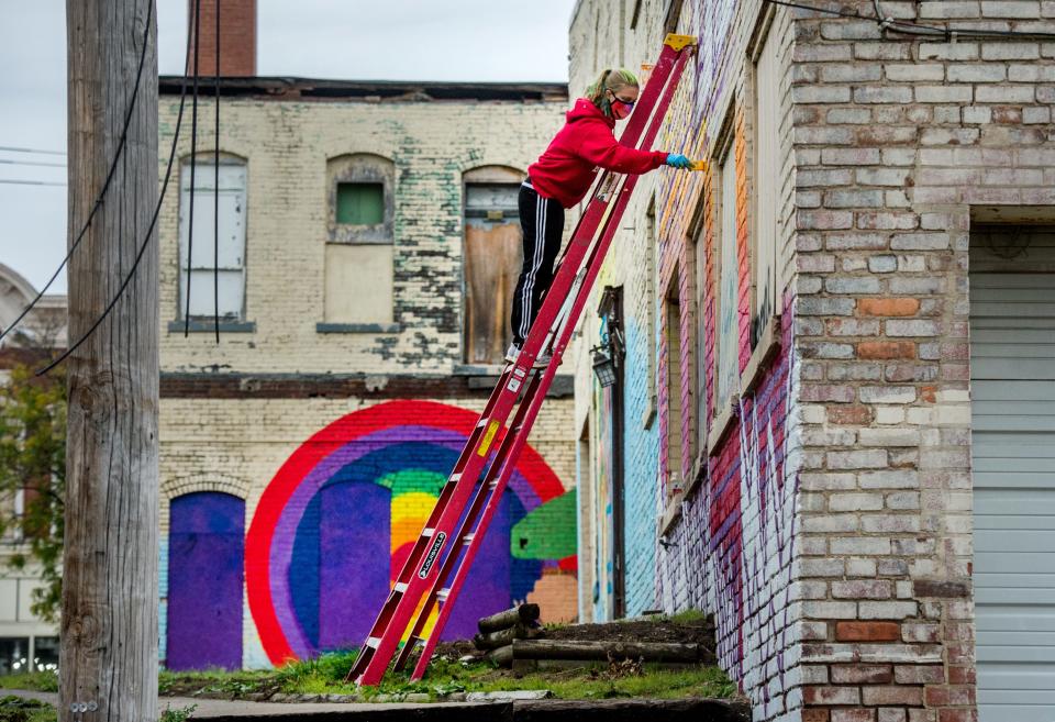 Bradley University senior chemistry major/art minor Cassidy Kraft works from atop a ladder on a mural on the side of an old building Wednesday, Oct. 22, 2020 in Peoria's Warehouse District.