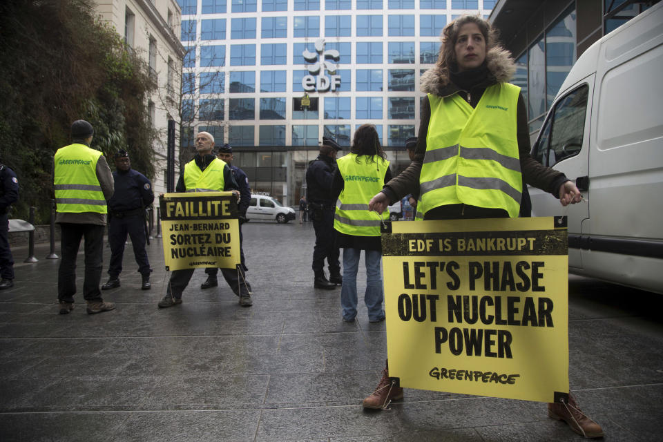 FILE - Greenpeace activists hold placards during the presentation of EDF group's 2016 results in Paris, Feb. 14, 2017. Greenpeace accuses the French nuclear industry of fobbing off waste on other countries and covering up problems at nuclear facilities, which industry officials deny. (AP Photo/Thibault Camus, File)